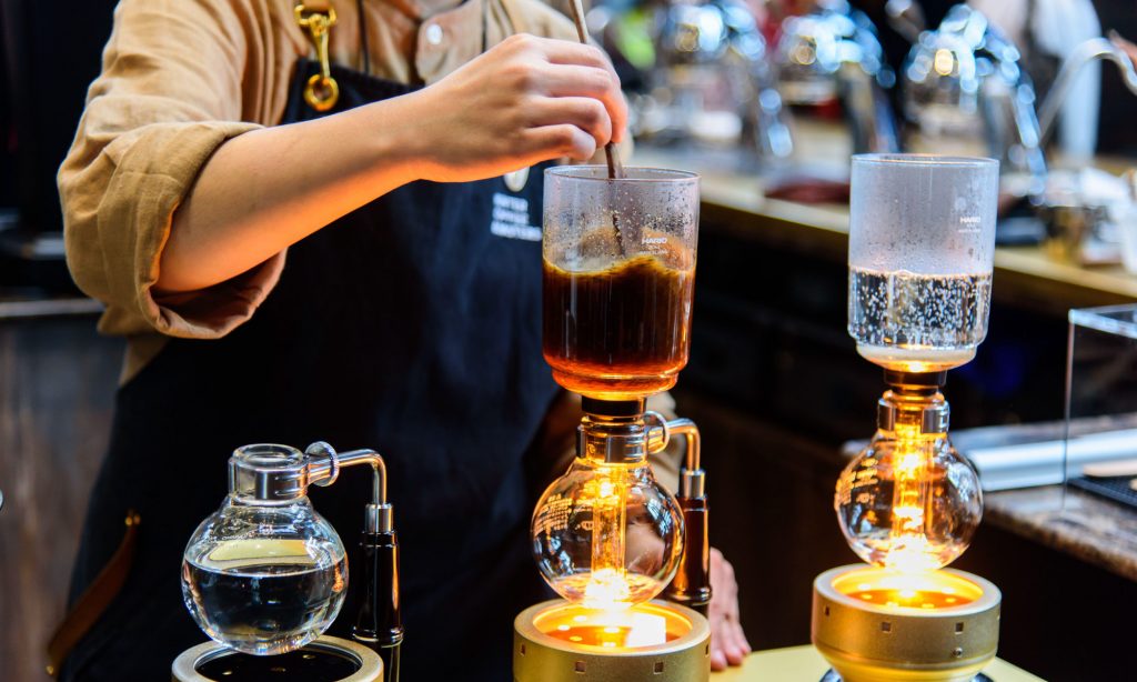 A specialty coffee barista prepares siphon coffee in a coffee shop in Bangkok, Thailand.