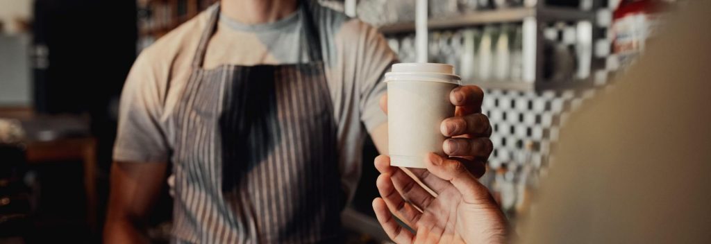 barista handing over a takeaway coffee